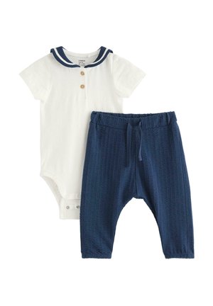 Hvid babyheldragt med korte ærmer, navy sømandshals og to knapper, kombineret med teksturerede navy blå elastiske bukser.