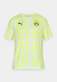 Jersey de manga corta en amarillo neón con un patrón geométrico, que presenta un logo de Puma negro y un escudo de equipo circular negro en el pecho.