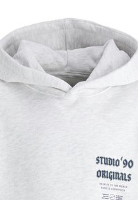 Light grey hoodie with a soft texture, featuring a large hood and a print on the front reading "STUDIO '90 ORIGINALS."