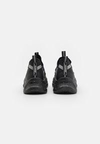 Czarne buty sportowe z teksturowanej tkaniny, w szaro-czarny wzór i nakrapianą podeszwą. Posiadają pętle do zakupu na pięcie.