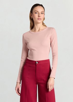 Top a maniche lunghe a costine in rosa tenue, abbinato a pantaloni a gamba larga a vita alta in rosso intenso. Presenta una scollatura rotonda e una texture sottile.