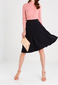 Musta liehukehelmainen hame, kevyt kangas, keskipitkä. Yhdistetty vaaleanpunaiseen ribbineulottuun pitkähihainen toppiin ja nudenväriseen clutch-laukkuun, jotka täydentävät vaaleanpunaiset korkokengät.