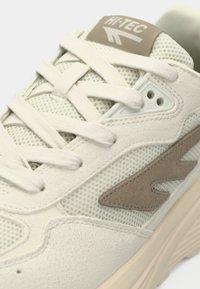 Sneakers in light cream and beige, featuring a mesh upper, soft suede accents, round laces, and a textured rubber outsole.