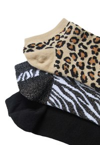 Tre paia di calze: una color crema con stampa leopardata, una nera con strisce bianche a zebra e una nera tinta unita con una finitura testurizzata.