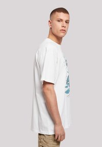 White cotton t-shirt featuring a graphic print in blue tones, short sleeves, and a relaxed fit, with a straight hem and crew neck.