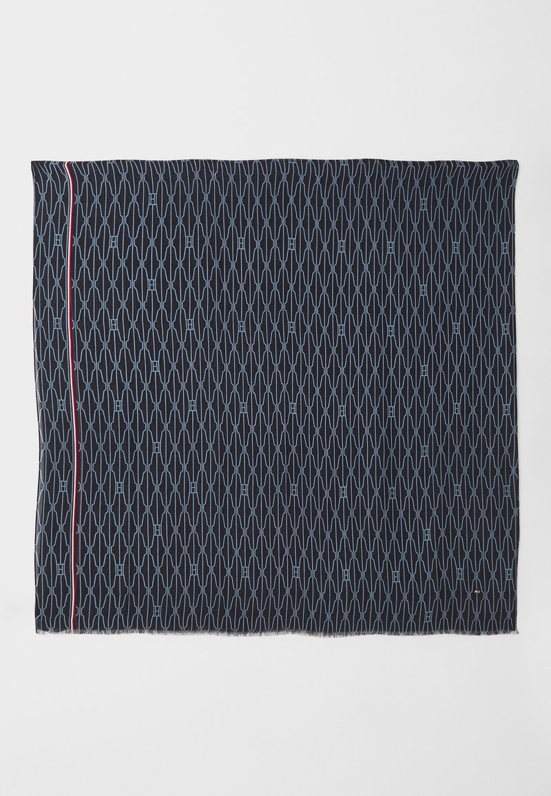 Tissu bleu marine avec un motif géométrique en bleu clair, présentant une bande d'accent rouge sur un bord et des extrémités à franges.