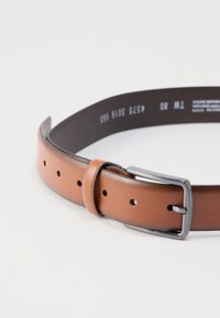 Brauner Ledergürtel mit glatter Oberfläche, silberner Metallschnalle und mehreren Einstelllöchern entlang der Länge.