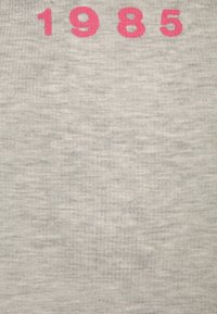 Grå tygtröja med stora, ljusrosa tryckta siffrorna "1985" över bröstet. Mjuk textur med en något melerad look.