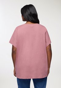 Różowa, oversize'owa koszulka z miękkiej bawełny, posiada krótki rękaw, okrągły dekolt i lekko zaokrąglony dół.