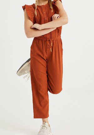 Combinaison couleur rouille en tissu texturé, manches courtes à volants, taille élastique, cordon de serrage, jambes fuselées arrivant à la cheville.