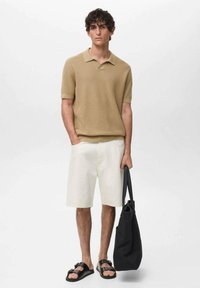 Tan ribbed polo shirt with short sleeves, white shorts, black sandals, and a black tote bag. Simple and casual summer outfit.
