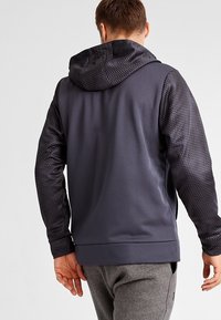 Felpa con cappuccio da uomo in grigio scuro con maniche in tessuto decorato. Presenta un corpo liscio, un design sportivo e un cappuccio regolabile.