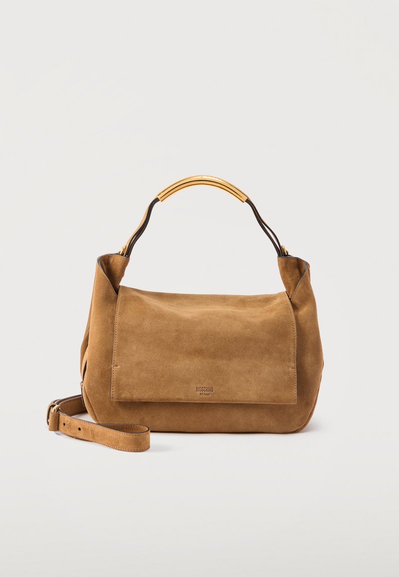 Καφέ σαμουά τσάντα Moschino με χρυσόχρωμη κυρτή λαβή και ρυθμιζόμενο λουρί ώμου σε απλό φωτεινό φόντο.