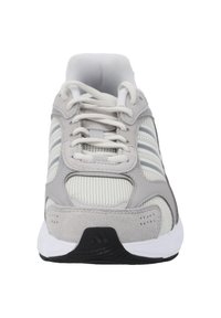 Scarpa atletica grigia con tomaia in rete, dettagli in suede, lacci bianchi e suola nera testurizzata. Design a tre strisce sui lati.