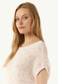 Hellrosa gestrickter Pullover mit lockerer Passform, rundem Ausschnitt und kurzen, umgeschlagenen Ärmeln. Besticht durch ein strukturiertes Muster mit dezenten Sprenkeln.