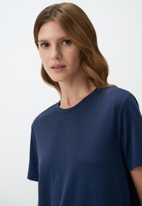 Marineblauwe katoenen t-shirt met een ronde halslijn, korte mouwen en een zachte textuur. Beschikt over een relaxte pasvorm en een minimalistisch ontwerp.
