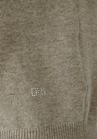 Brauner Strickpullover aus texturiertem Stoff, verziert mit Strasssteinen, die "Oui" auf der Vorderseite bilden.