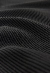 Tessuto nero a coste con linee orizzontali distinte, caratterizzato da una texture morbida e un leggero splendore, disposto in pieghe morbide.