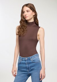 Body senza maniche marrone con colletto alto, realizzato in un tessuto liscio e elasticizzato, abbinato a jeans a vita alta blu chiaro.