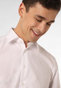 Witte katoenen overhemd met een verspreide kraag, met een gladde structuur en een standaard knoopsluiting. Licht gekreukt stof.