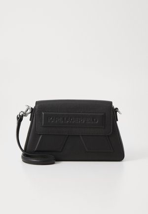 Black leather crossbody bag with a geometric design, featuring a flap closure and embossed logo. Adjustable strap and smooth texture.
