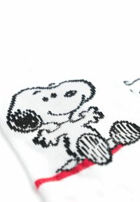 Calzini con un tessuto bianco che presenta un design a cartone animato di Snoopy in nero e dettagli rossi, caratterizzati da una texture liscia e un motivo giocoso.