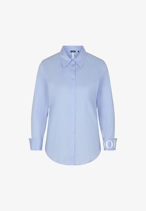 Chemise bleu clair à boutons, avec un col évasé, des manches longues, et un détail de logo sur les poignets. Tissu lisse avec une coupe légèrement ajustée.