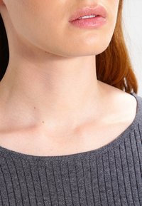 Grå, ribbad tröja med vid halsringning, åtsittande textur och mjukt tyg, bärs över bar hud och visar känsliga områden av nyckelbenet.