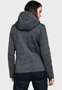 Chaqueta con capucha de tela gris texturizada con un patrón de espiga, que presenta una silueta ajustada y mangas largas.