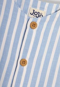 Camisa a rayas en azul claro y blanco con escote de botones, que presenta botones beiges y una etiqueta cosida en el interior del cuello.