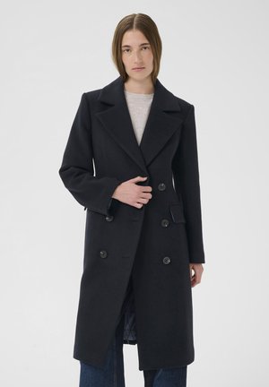 Manteau en laine noir à double boutonnage avec grands revers, deux boutons, poches latérales et doublure matelassée.