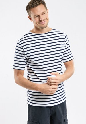 T-shirt à rayures blanc et marine, manches courtes, col rond, tissu doux, coupe décontractée, porté avec un short cargo foncé.