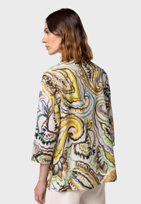Giacca colorata con motivo floreale, realizzata in tessuto fluido, maniche a tre quarti e vestibilità ampia. La vista posteriore mostra dettagli di design intricati.