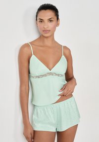 Conjunto de dormir en verde menta que incluye un top ligero con encaje y shorts a juego con una sutil textura estampada.