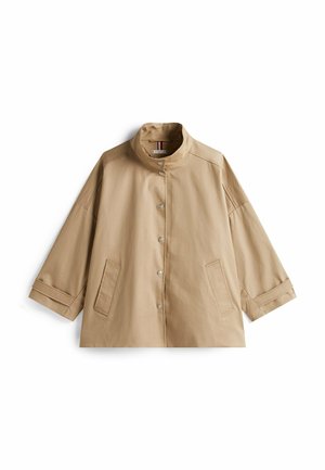 Veste légère beige avec un col haut, des boutons-pression et deux poches avant. Dispose de larges manches trois-quarts et d'une texture lisse.