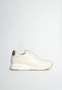 Baskets basses couleur crème avec talon texturé, design à lacets, et semelle en caoutchouc beige, présentées de profil sur un fond blanc.