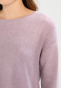 Suéter de punto morado con un escote ancho y textura acanalada a lo largo de las mangas, hecho de un material suave y ligero.