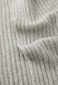 Tejido de punto gris acanalado con una textura suave, que presenta rayas verticales y sutiles variaciones de color. El tejido parece cálido y acogedor.