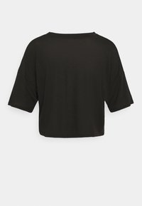 Musta lyhythihainen paita, jonka istuvuus on väljä ja kaula-aukko on pyöreä. Valmistettu pehmeästä kankaasta, siinä on lyhyt malli ja väljät hihansuut.