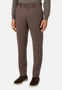 Hnědé kalhoty z vlněné směsi se slim fit střihem, vybavené dvěma knoflíky, bočními kapsami a hladkou texturou. V kombinaci s tmavými mokasíny.