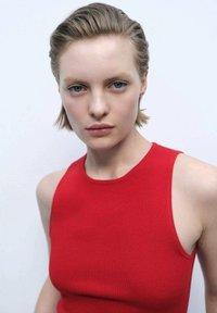 Red sleeveless knit top with a rounded neckline, smooth texture, and close fit. Background is plain white, emphasizing the garment.