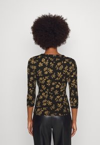 Black floral top features a fitted design with 3/4 length sleeves and gold floral patterns. Smooth fabric with a slight sheen.