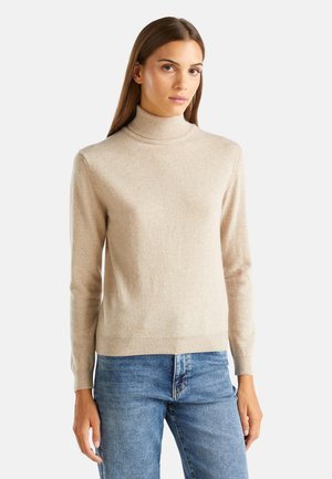 Beige turtleneck sweater made of soft fabric; ribbed cuffs and hem; fitted design; worn with blue jeans.