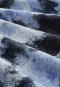 Tessuto in pile nelle tonalità di blu e nero, con una morbida texture caratterizzata da un motivo marmorizzato e pieghe lisce e ondulate.