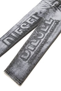 Jeans em denim numa cor mesclada de preto e cinza, apresentando gráficos de texto em relevo. Estilo clássico de cinco bolsos com um corte slim e costura detalhada.