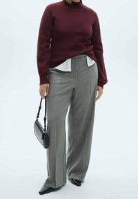 Pull en tricot bordeaux et pantalon large à carreaux gris. Les accessoires comprennent un petit sac à main noir. Texture lisse et coupe ajustée visibles.