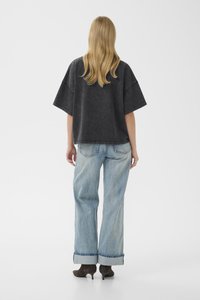 Løs svart denimbluse med vide ermer, kombinert med blå høy midje jeans med oppbrettede mansjetter og strukturert stoff.