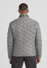 Graue gepolsterte Jacke mit einer strukturierten Steppoptik, die einen Stehkragen und eine glatte, glänzende Oberfläche aufweist.