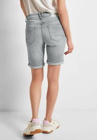 Bermuda in denim grigio con risvolti; due tasche posteriori con dettagli cuciti. Indossate con sneakers bianche con accenti rosa e giallo.