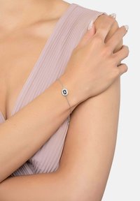 Hopeaketju hopeasta, jossa on suorakulmainen musta jalokivi, sekä huolellisesti valmistetut ketjureunat ja koristeelliset yksityiskohdat kiven ympärillä.